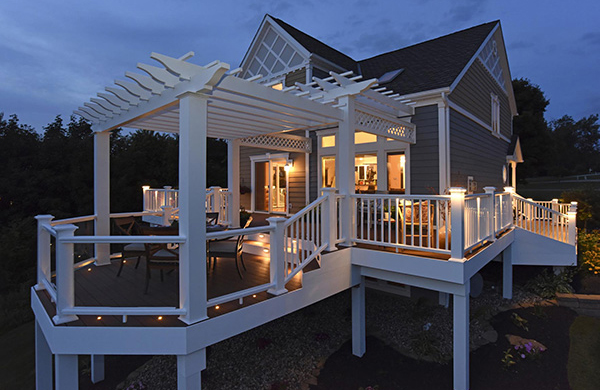 Dusk shot of a home with lighted white decking railing, mahogany composite decking and pergola