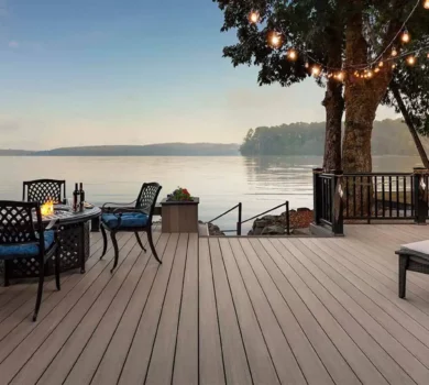 Light deck next to water with table and tree with lights
