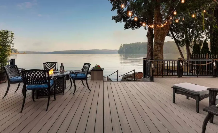 Light deck next to water with table and tree with lights
