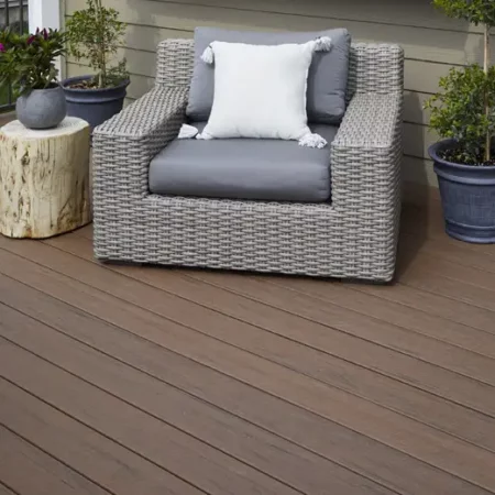 Deck ideas: Large wicker chair with plant on wooden stump as side table and two large potted plants behind