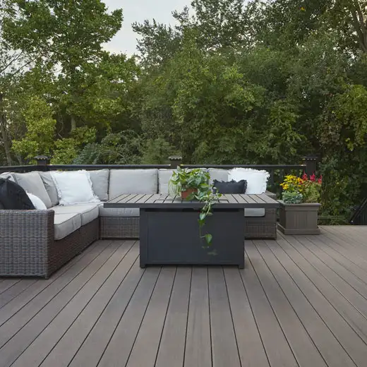 Deck ideas: Brown decking with large sectional. Coffee table made from fascia with plants on top, planter next to seating