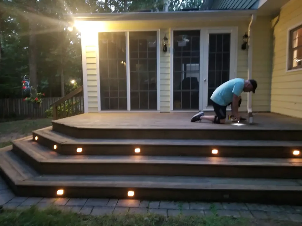 Man kneels on TimberTech decking with drill in the evening