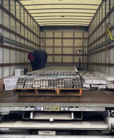2 men load decking and other merchandise onto a delivery truck