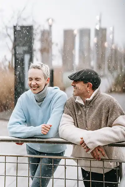 A man and a woman leaning up against a railing