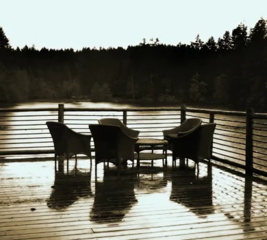 A serene water front deck at dusk with table and chairs in the foreground
