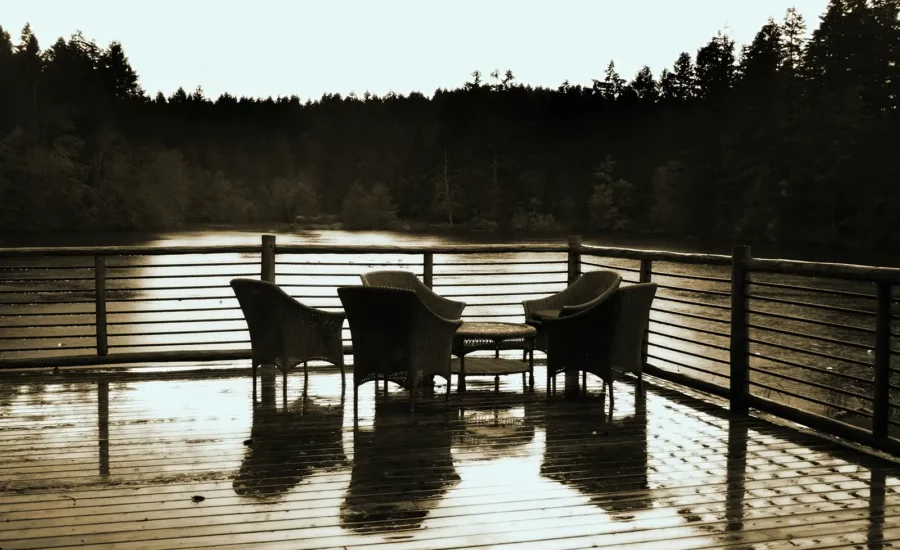 A serene water front deck at dusk with table and chairs in the foreground