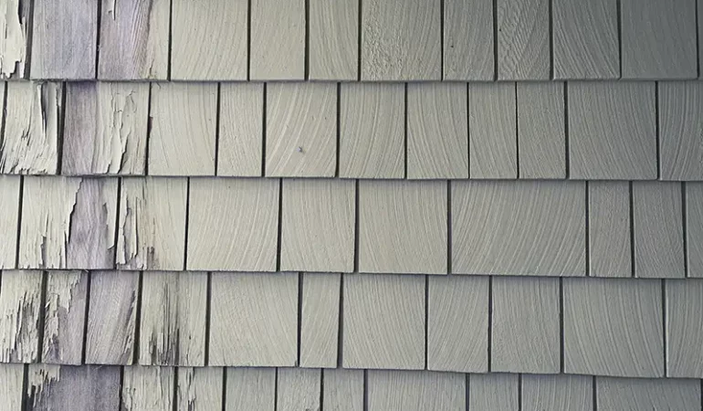 Building exterior with cedar lap siding with chipped paint.