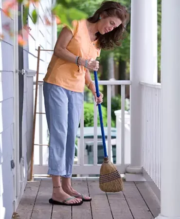 A woman sweeping her deck.