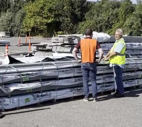 Two men in safety vests standing next to a lumber pallet at warehouse '71.