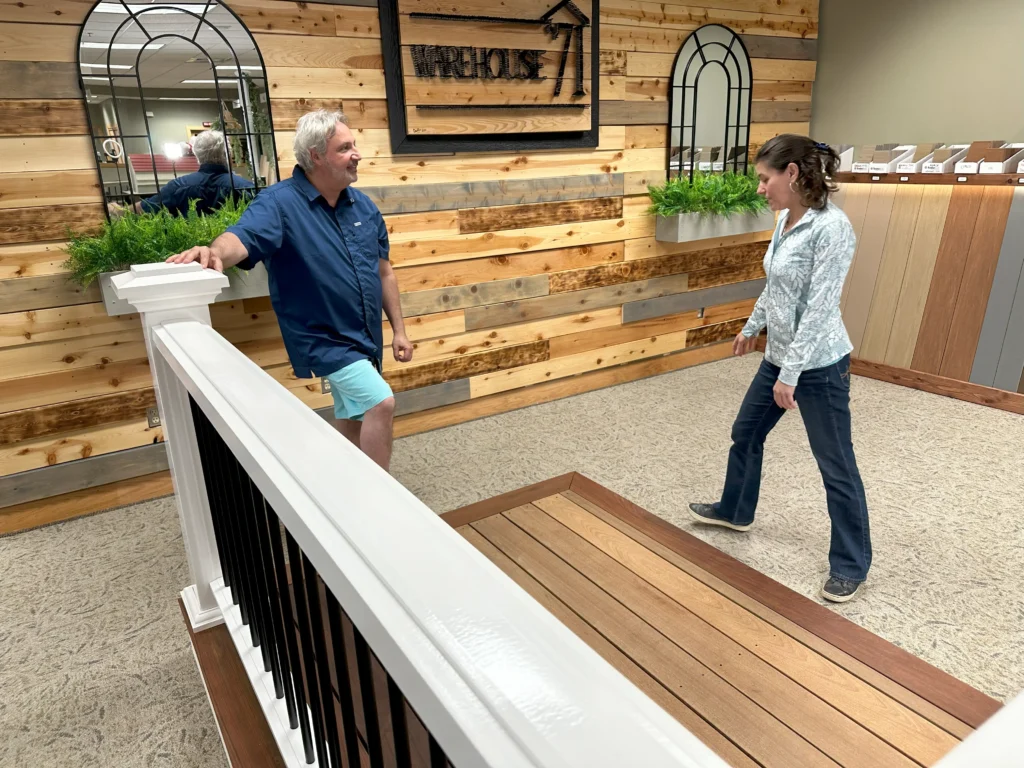 A man is helping a woman who is looking at decking and railing options.