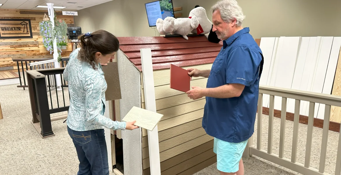 A man helps a woman pick out siding samples from a display.